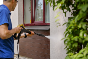 a person power-washing their home before painting 